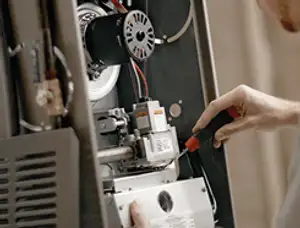 Furnace repair technician inspecting internal components and wiring in Saint Charles, MO