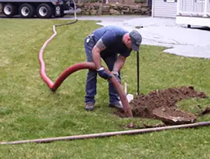 Septic pumping technician servicing a residential septic tank with a vacuum hose in Saint Charles, MO