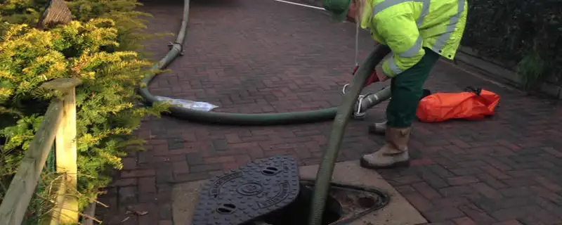 Septic tank cleaning technician servicing a septic tank with a vacuum hose in Saint Charles, MO