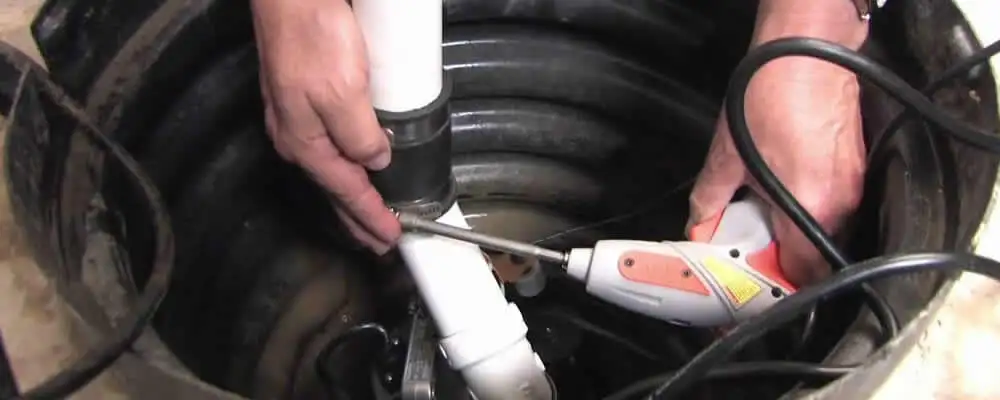 Sump pump installation technician connecting PVC discharge piping in Saint Charles, MO