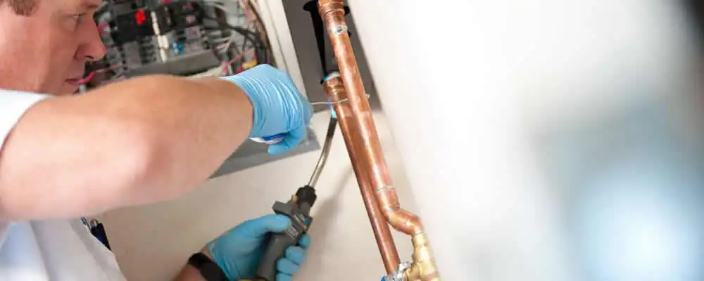 Water heater repair technician testing copper pipe connections and controls in Saint Charles, MO